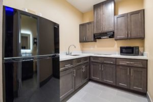 Full size fridge freezer, wall and base cabinets, counter top with sink, hob and microwave, tiled flooring