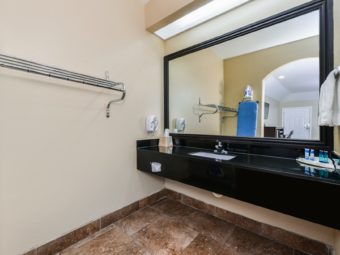 Vanity unit with bathroom amenities, mirror, wall mounted shelf, tiled flooring