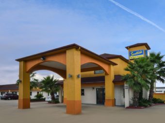 Hotel entrance with canopy drive through, landscaping with shrubs, flowers and trees