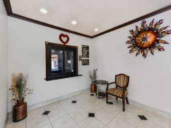 Guest check in desk, vase with dried flowers, occasional table, chair, tiled flooring