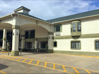 Canopied hotel entrance, vending machine, two story building with exterior room entrances with covered walkways and stairs