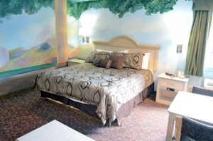 Wall murals, king bed, night stands with telephone and clock, small table and chairs, carpet flooring