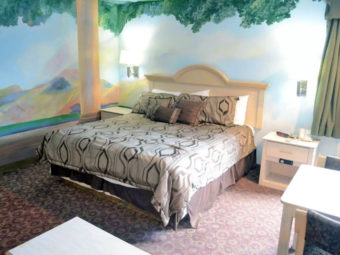 Wall murals, king bed, night stands with telephone and clock, small table and chairs, carpet flooring