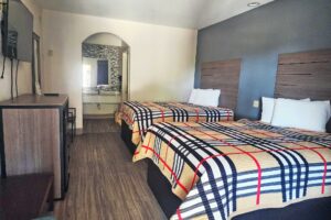 Two queen beds, night stand with telephone, wooden unit, wall mounted TV, mirror, alcove with vanity unit and mirror, laminate flooring