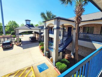 Hotel entrance with drive through canopy, two story building with exterior guest room entrances, covered walkways and stairs, parking spaces