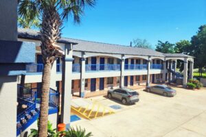 Two story building with exterior guest room entrances, covered walkways and stairs, parking spaces