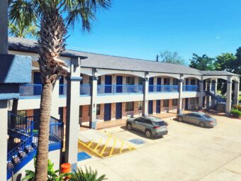 Two story building with exterior guest room entrances, covered walkways and stairs, parking spaces