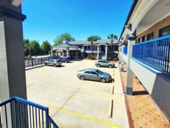 Two story building with exterior guest room entrances, covered walkways and stairs, parking spaces, hotel entrance with drive through canopy