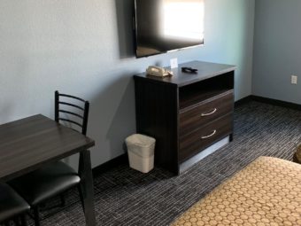 Wooden unit, wall mounted flat screen tv, small table and chairs, carpet flooring