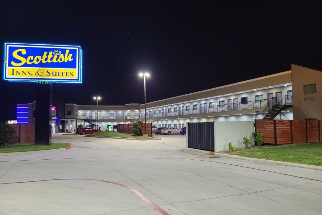 Branded signage, two story building with exterior walkways, stairs and room entrances, parking areas