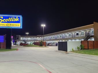 Branded signage, two story building with exterior walkways, stairs and room entrances, parking areas