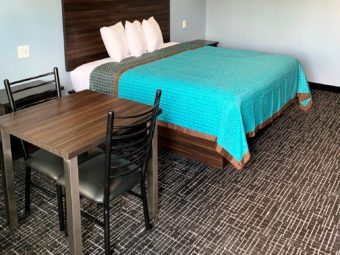 king bed, night stands, small table and chairs, carpet flooring