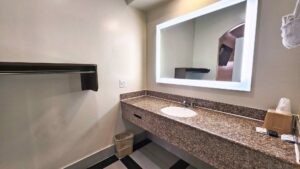 Shelf with hanging rail, vanity unit, back-lit mirror, towel rail with towels, tiled flooring