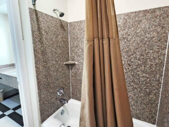 Shower tub with shower curtain, doorway to vanity unit, tiled flooring