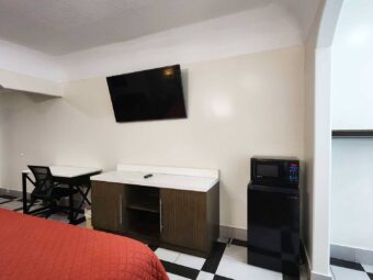 King bed, desk with chair, storage unit, wall mounted TV, mini fridge with microwave, tiled flooring