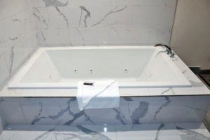 Jacuzzi tub, bath mat, tiled surround