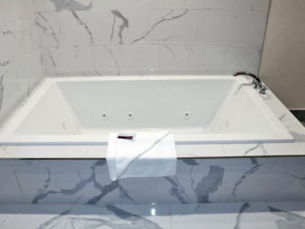 Jacuzzi tub, bath mat, tiled surround