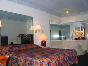 King bed, jacuzzi tub, mirrored surround, night stand with bedside lamp, carpet flooring