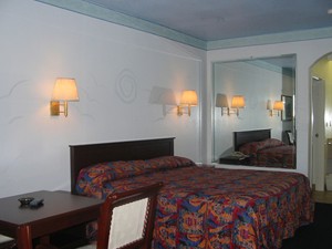 King bed, mirrored walls, wall mounted bedside lights, small table and chair