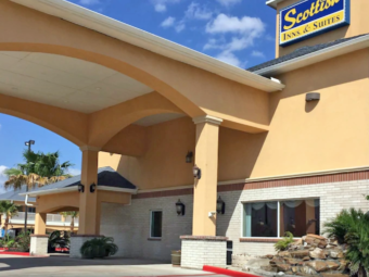 Hotel entrance with canopied drive through, landscaping with trees