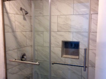 Shower with glass doors and tiled surround