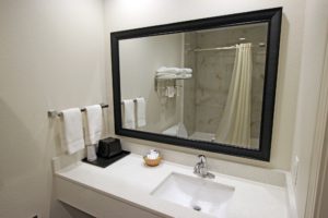 Vanity unit with sink, mirror, towel rail with towels, shower tub with shower curtain