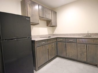Kitchenette with hob, sink, wall and base cabinets, fridge, tiled flooring