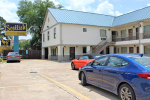 Hotel entrance, two story building, exterior entrances to rooms with covered walkways and stairs, parking spaces