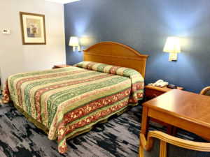 King bed, night stands with telephone and clock, art image and bedside lights, table and chairs, carpet flooring