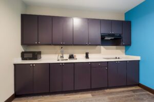 Wall cupboards with cooker hood, base cabinets with microwave, inset sink, coffee maker and hob, laminate flooring