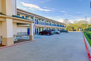 Two story building with exterior room entrances and walkways, parking spaces