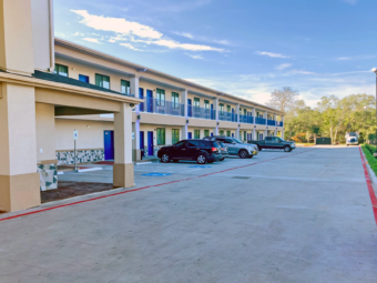 Two story building with exterior room entrances and walkways, parking spaces