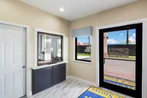 Hotel entrance door leading to guest chek-in desk, branded floor mat, tiled flooring