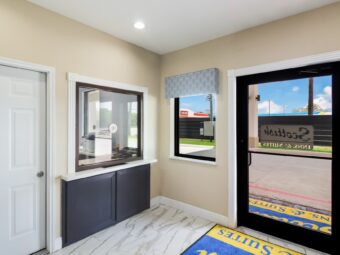 Hotel entrance door leading to guest chek-in desk, branded floor mat, tiled flooring