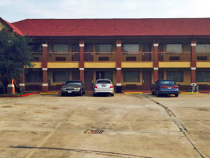 Two story building with exterior room entrances, covered walkways, parking spaces