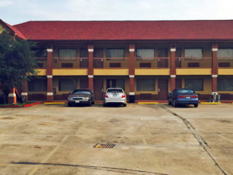 Two story building with exterior room entrances, covered walkways, parking spaces