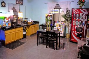 Table and chairs, easy chair, soda vending machine, breakfast counter display with juice machine, coffee machinem cereal dispensers, tiled flooring