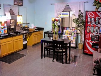 Table and chairs, easy chair, soda vending machine, breakfast counter display with juice machine, coffee machinem cereal dispensers, tiled flooring