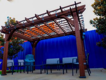 Pergola with lighting, chairs, occasional tables, bin, trees