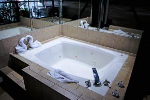 Jacuzzi tub, mirrored walls, bath mat , swan sgaoed towels, tiled surround