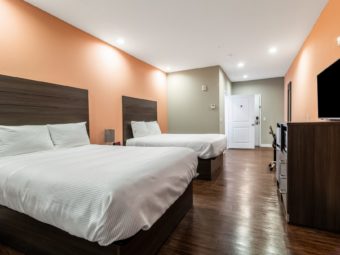 Two queen beds, night stand with bedside lamp, wooden unit with flat screen tv, laminate flooring