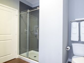 toilet, towel rail and shelf with towels, shower with glass door, laminate flooring
