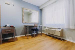 Desk with chair, night stand with telephone and clock, laminate flooring