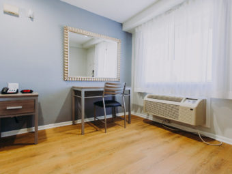 Desk with chair, night stand with telephone and clock, laminate flooring