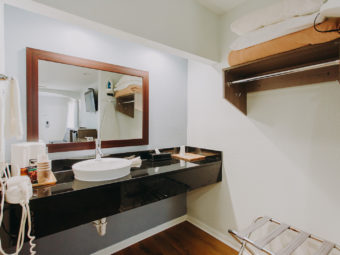 Vanity unit, hair dryer, towel rail with towels, mirror, hanging rail with overhead shelf, folding portable luggage rack, laminate flooring