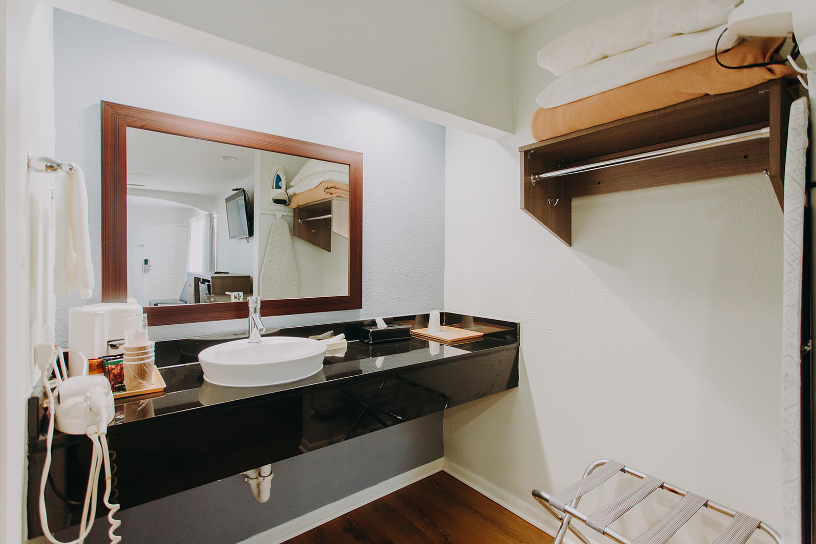 Vanity unit, hair dryer, towel rail with towels, mirror, hanging rail with overhead shelf, folding portable luggage rack, laminate flooring