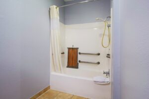 shower tub with shower curtain, towels, and grab handles, tiled flooring