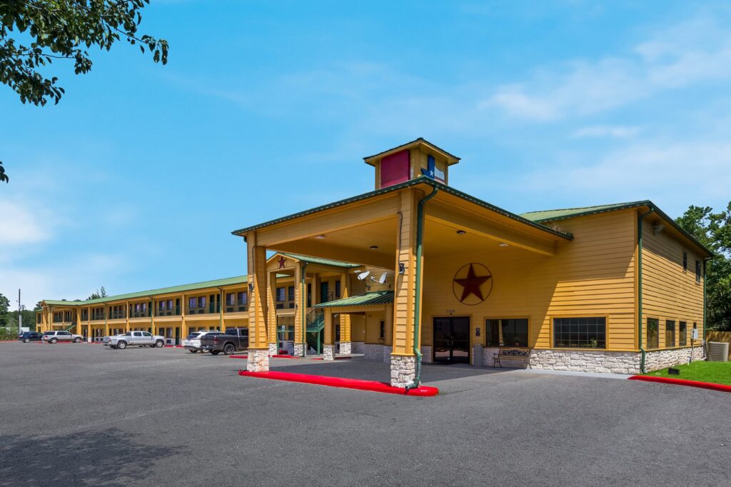 Hotel canopied drive trhough entrance, two story building with covered walkways and exterior guest room entrances, parking spaces