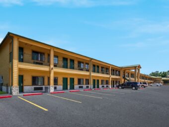 Two story building with covered walkways, stairways and exterior guest room entrances, parking spaces