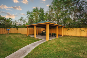 Guest covered BBQ area with grill, tables and seating, path and grassy areas